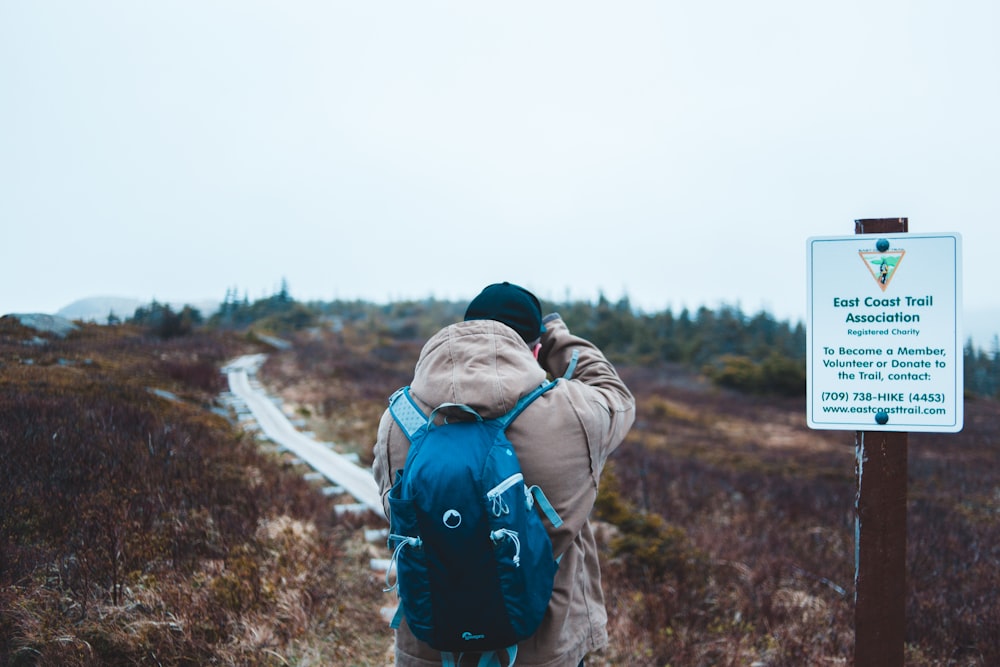 man standing beside road signage in an open field