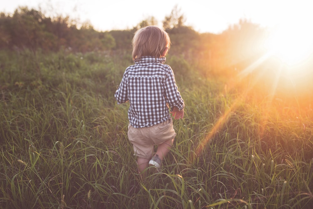 boy walking on grass field