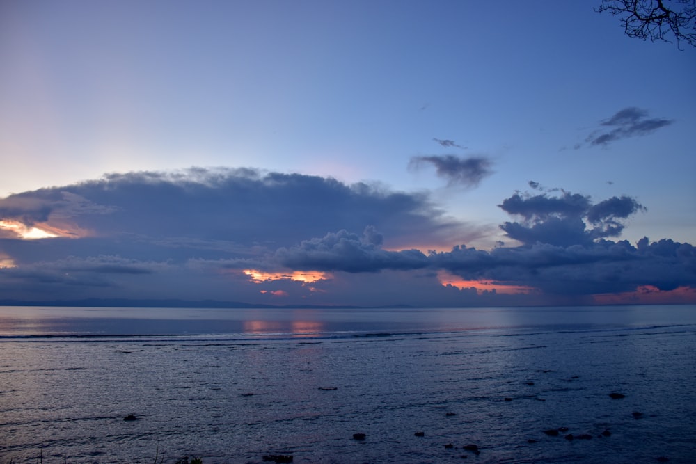 body of water under cloudy sky during golden hour