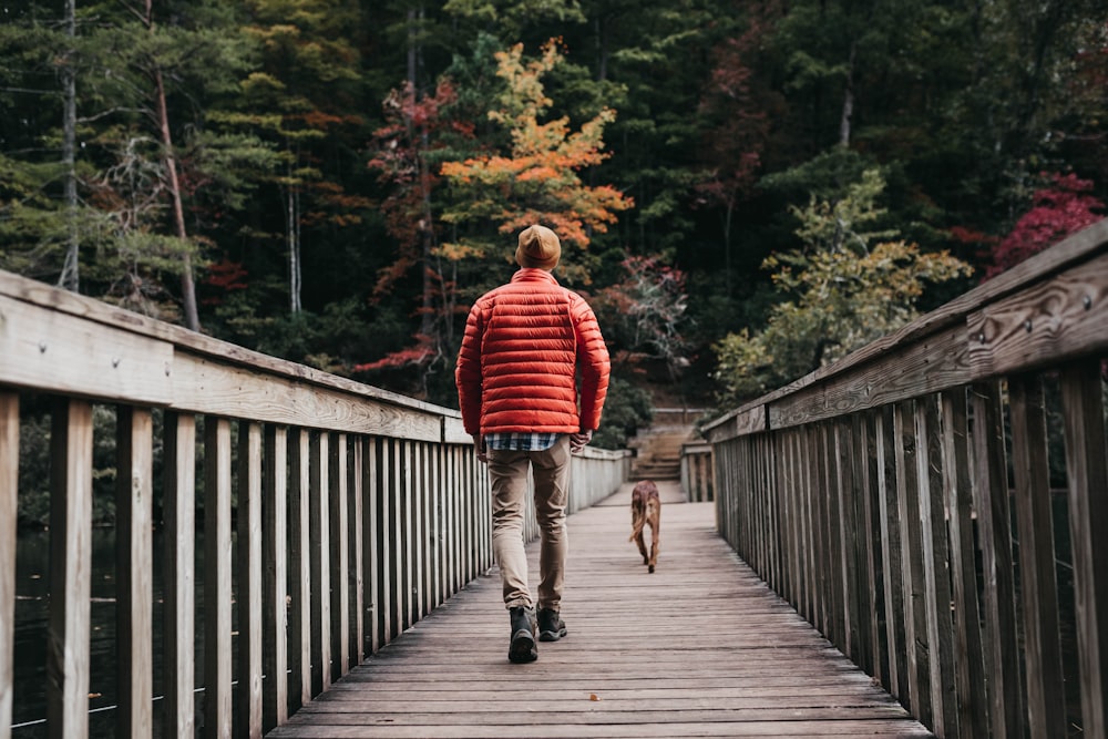 man walking on bridge beside dog during daytime