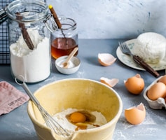 brown mixing bowl with eggs and flour with whisk