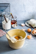 brown mixing bowl with eggs and flour with whisk