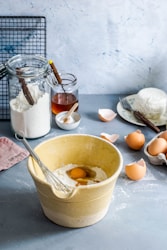 brown mixing bowl with eggs and flour with whisk