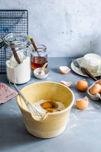 brown mixing bowl with eggs and flour with whisk