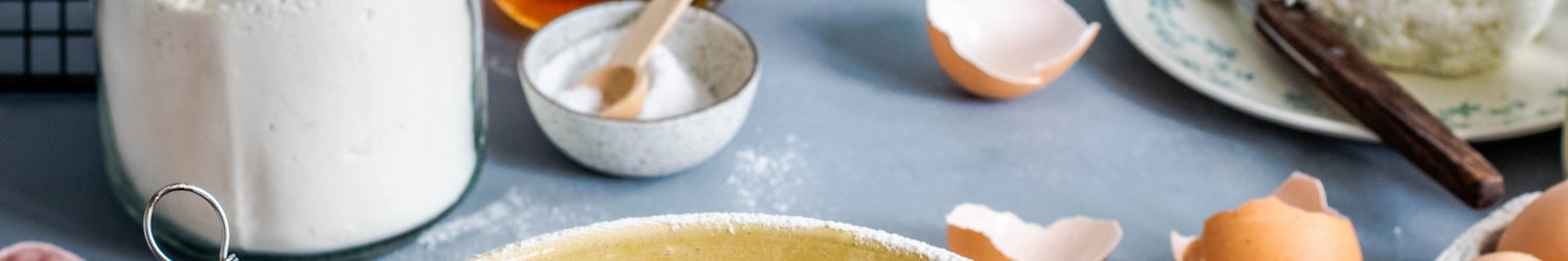 brown mixing bowl with eggs and flour with whisk