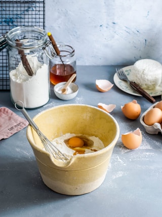 brown mixing bowl with eggs and flour with whisk