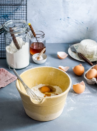 brown mixing bowl with eggs and flour with whisk