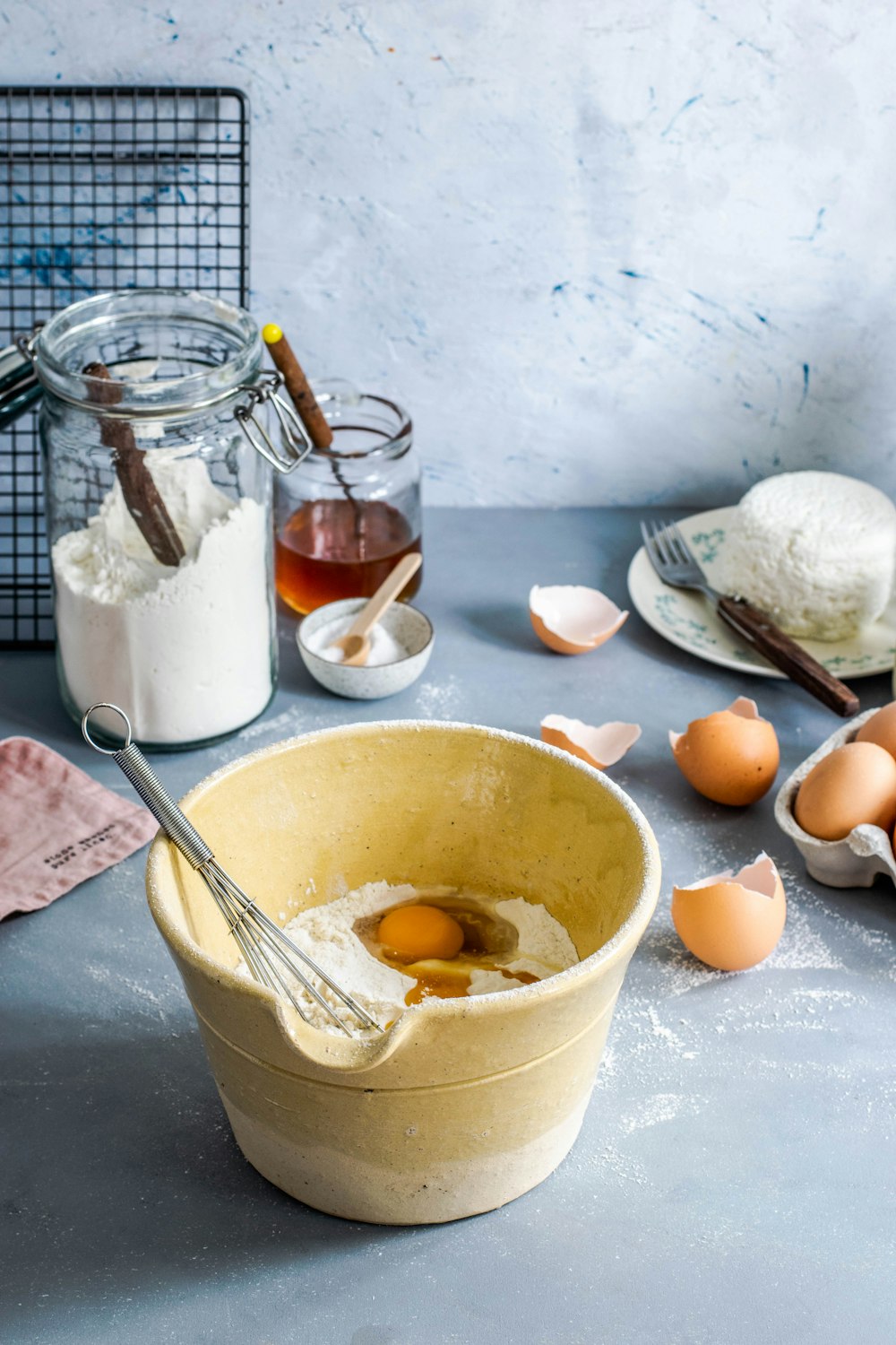 brown mixing bowl with eggs and flour with whisk