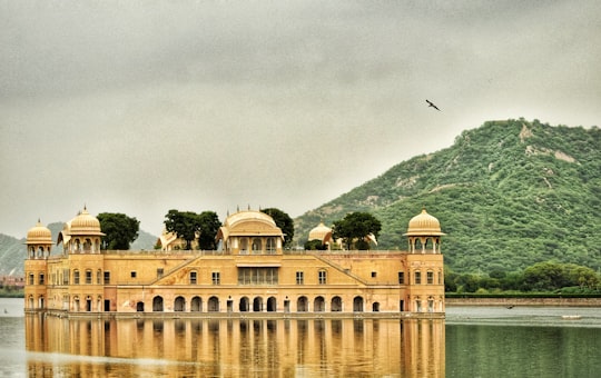 brown concrete building at water during daytime in Jal Mahal India