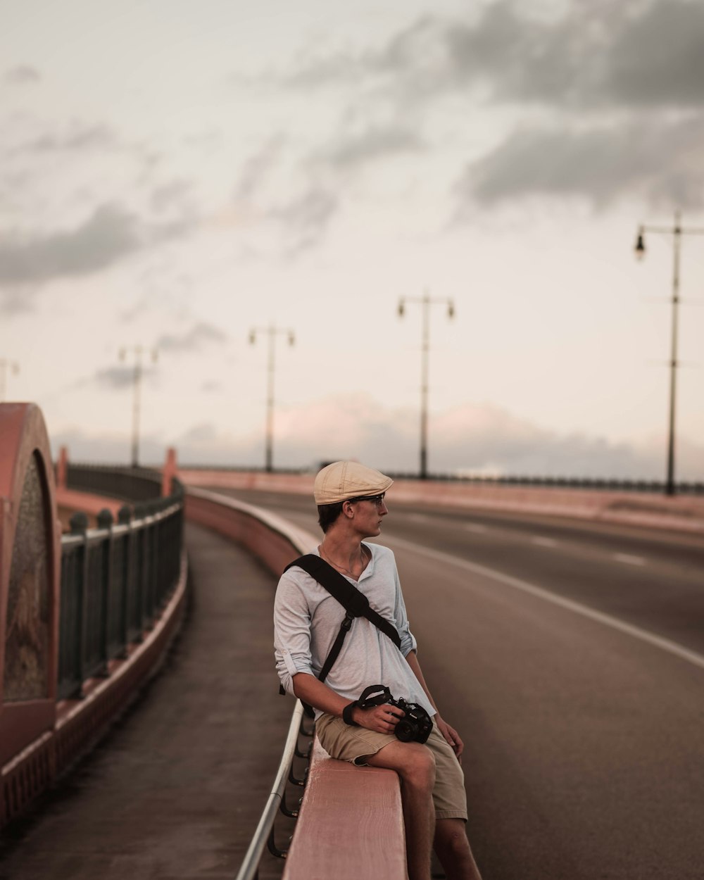 man wearing grey polo shirt sitting on road railings during daytime