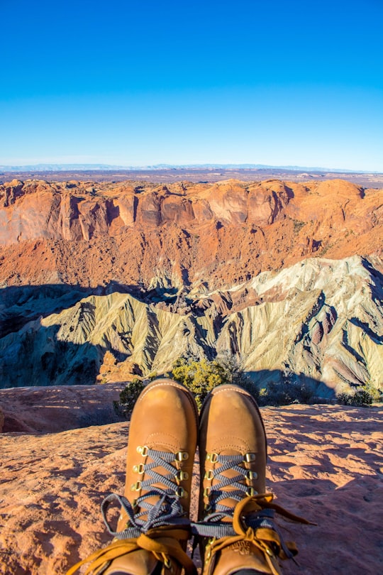 person sitting while facing on brown rocky mountain in Canyonlands National Park United States