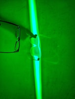 A vibrant blue and green eyeglass frame resting on a white surface.