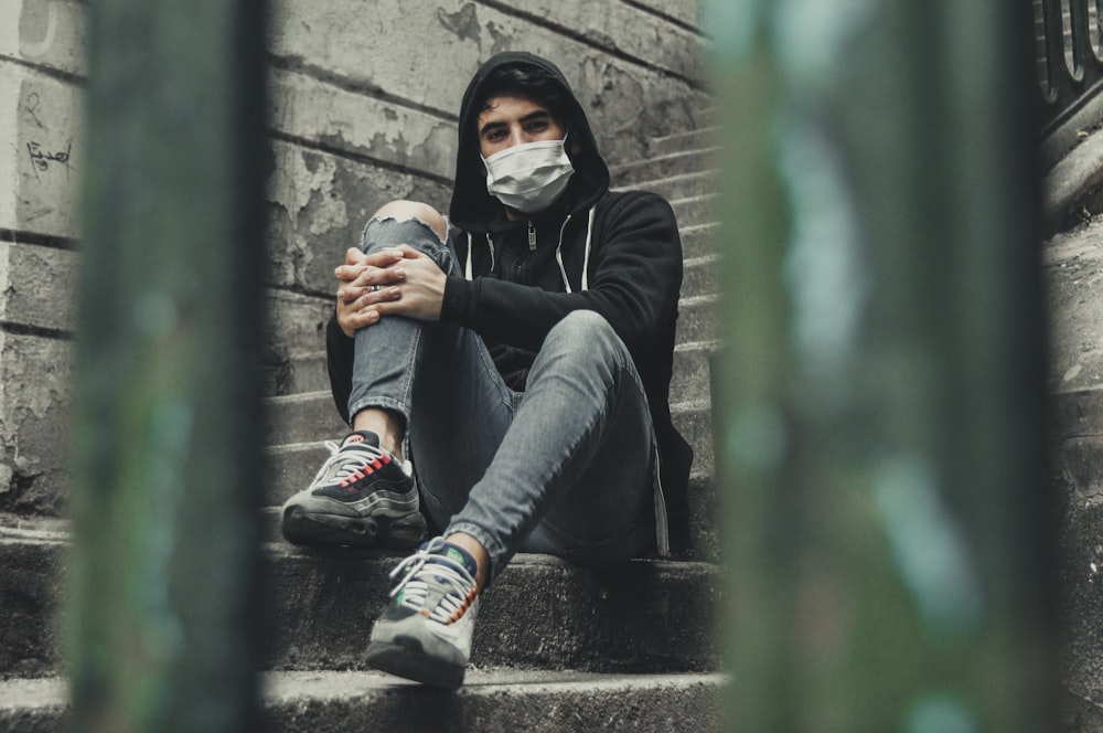 man sitting on staircase wearing face mask