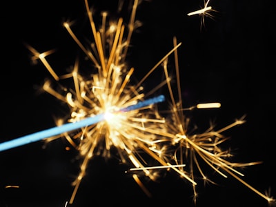 Close-up of sparks flying off a firework with glowing smoke trails.