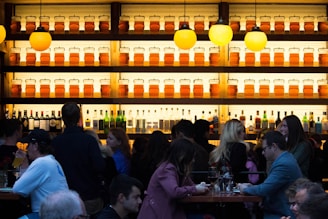 A bustling bar scene with numerous people socializing and drinking.