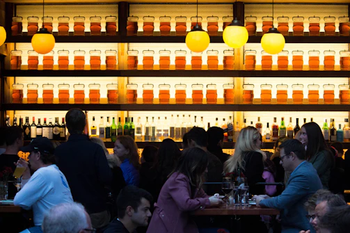 A lively bar scene with people enjoying drinks and live music under warm lighting.