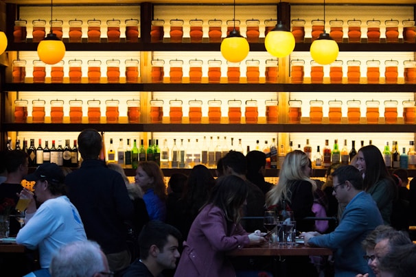 A bustling bar scene with numerous people socializing and drinking.