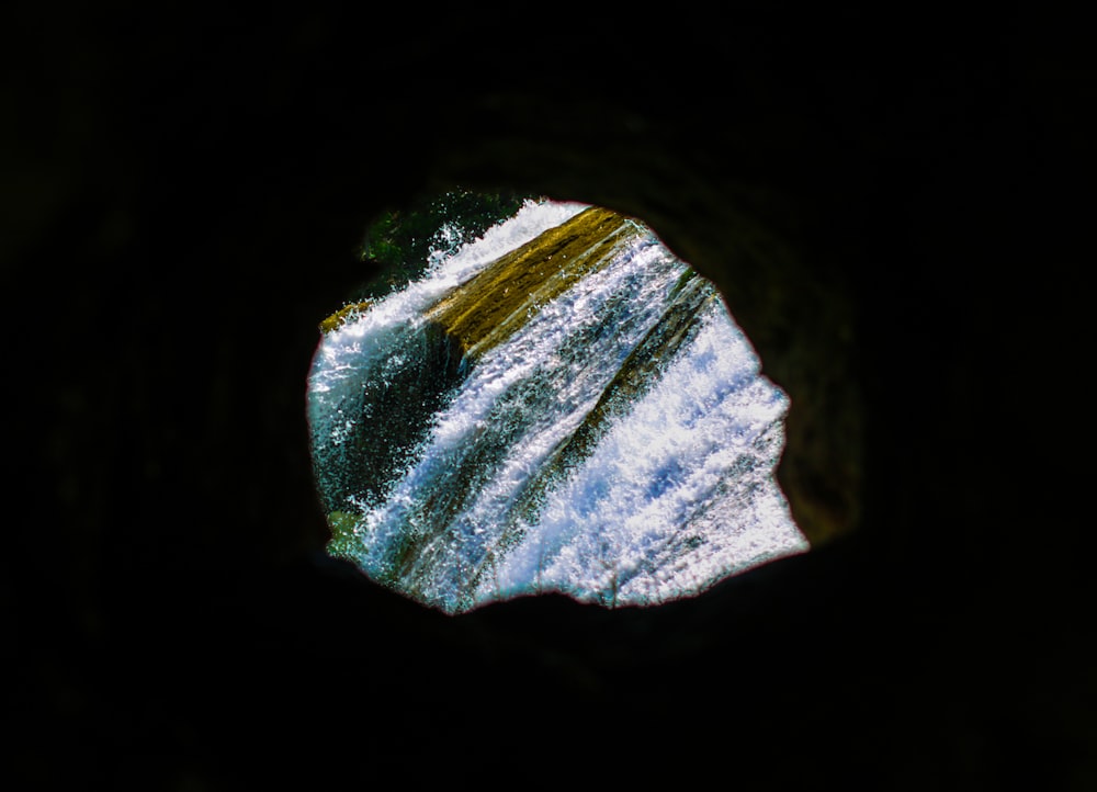 une vue d’une cascade à travers un trou dans un rocher