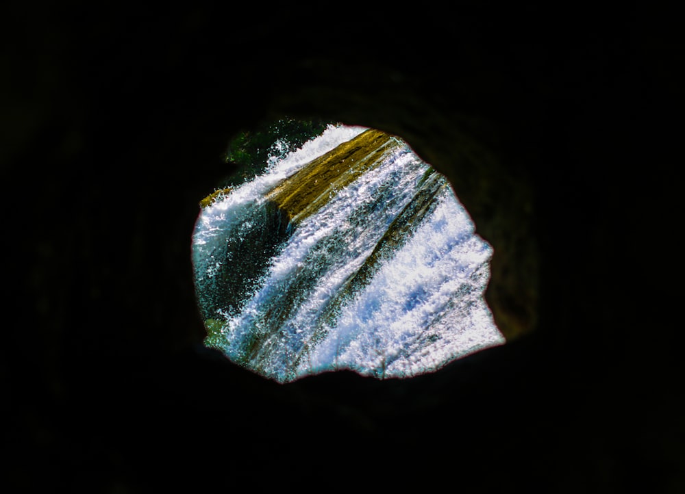 a view of a waterfall through a hole in a rock