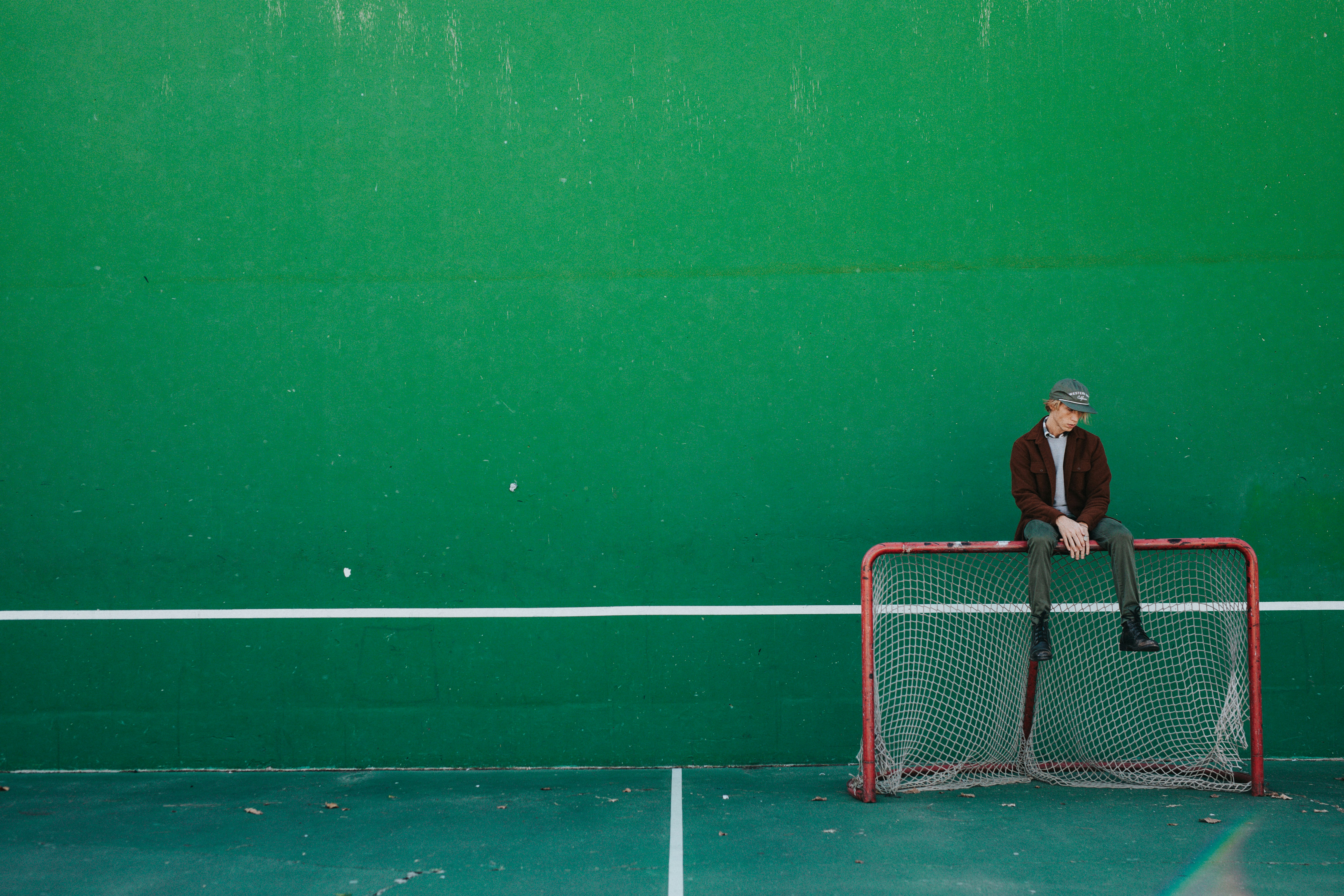 man sitting on brown and white goalie net