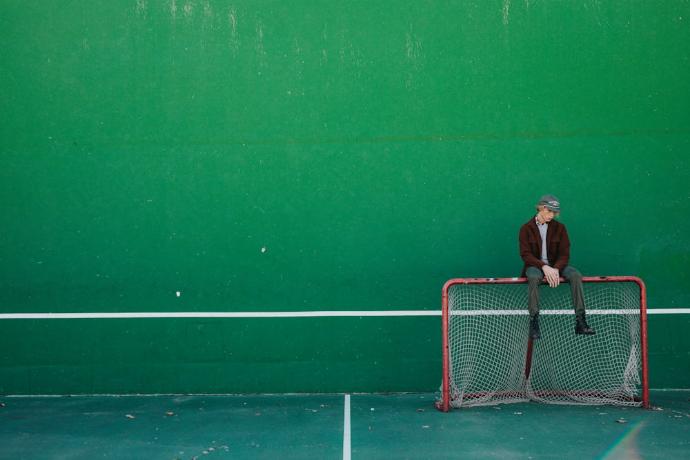 man sitting on brown and white goalie net