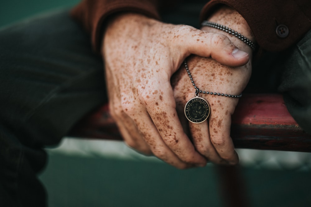 person holding round gold-colored necklace