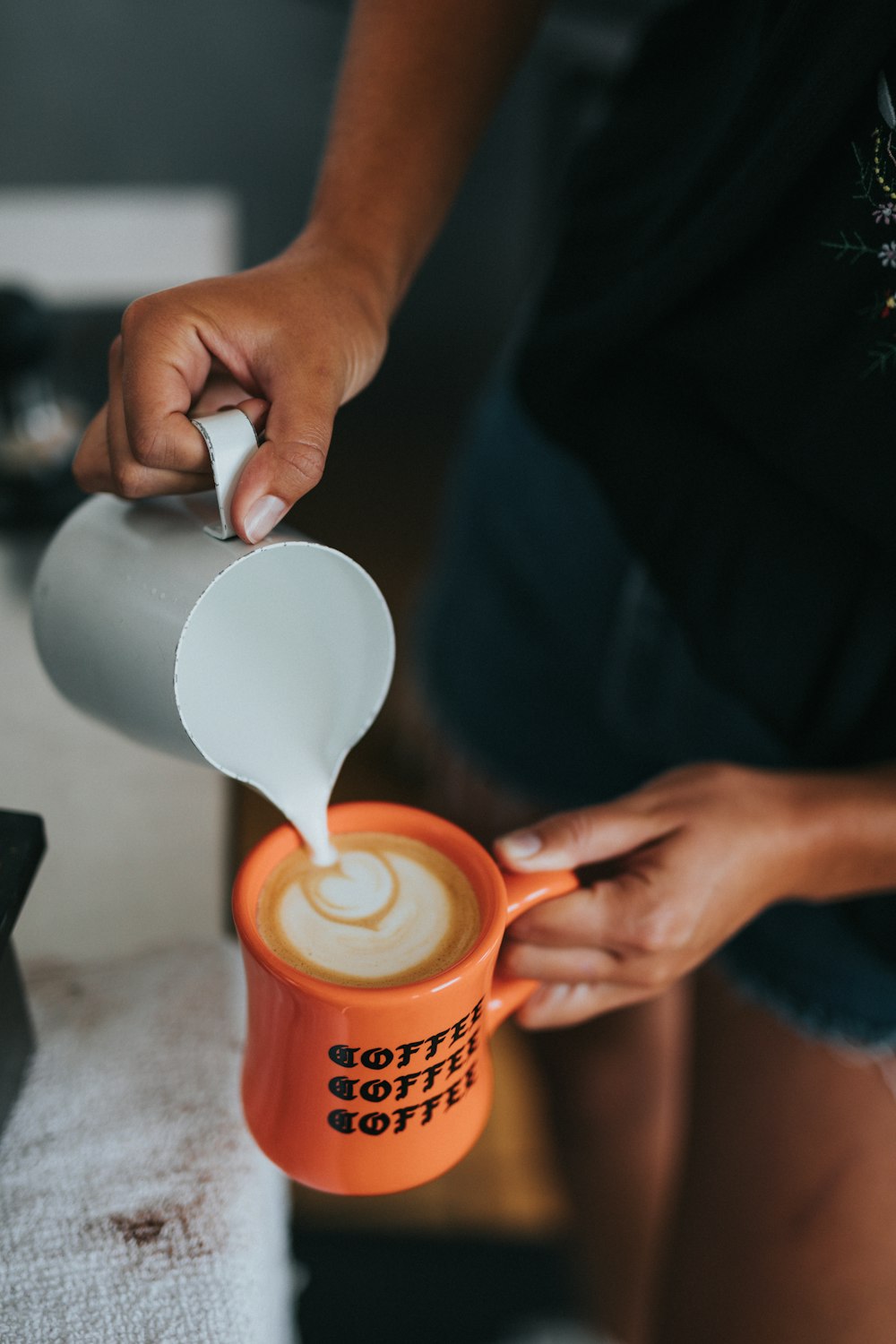 person pouring coffee on orange mug