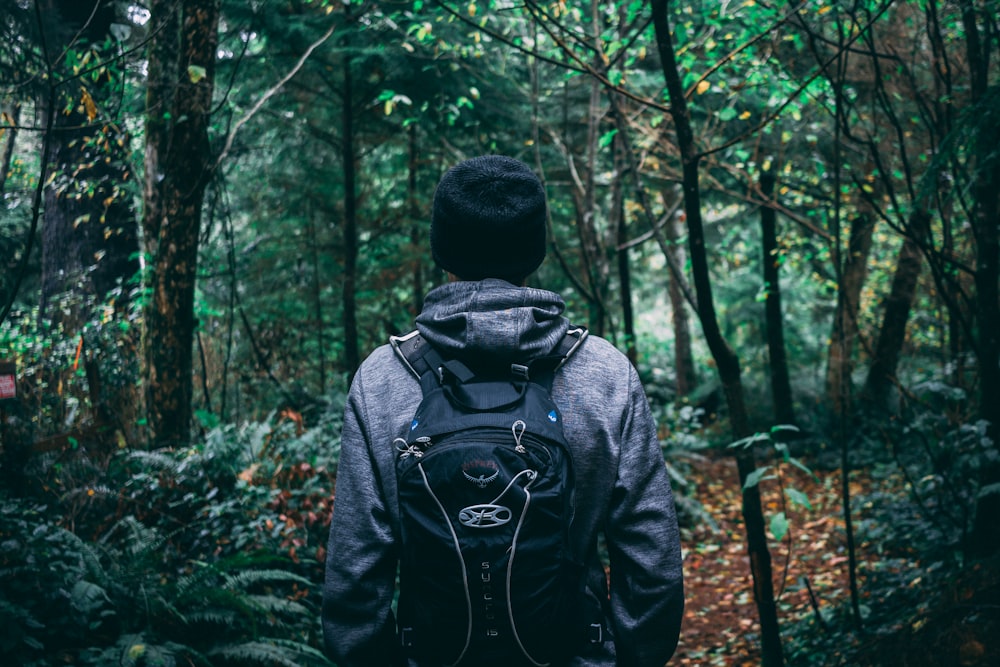 person in grey hoodie and black backpack in forest