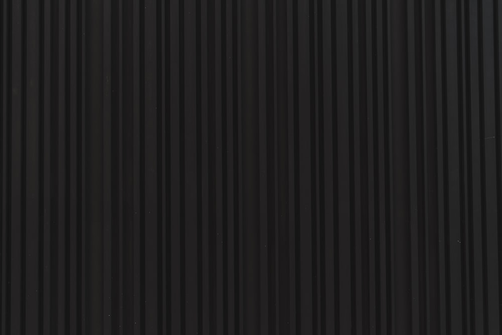 Eine Nahaufnahme einer schwarzen Wand mit vertikalen Linien
