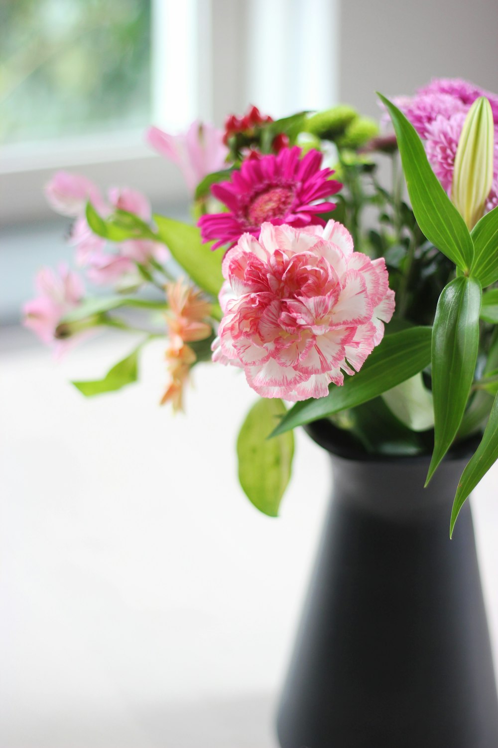 flowers in black vase on white surface