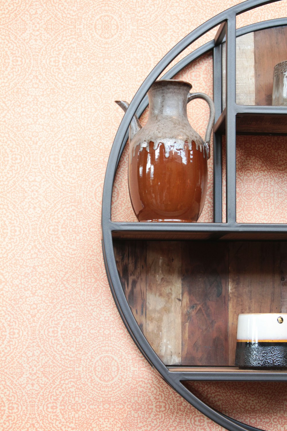 brown and gray ceramic pitcher on black wooden shelf