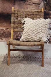 Soft linen cushions in olive tones arranged on a vintage wooden chair.