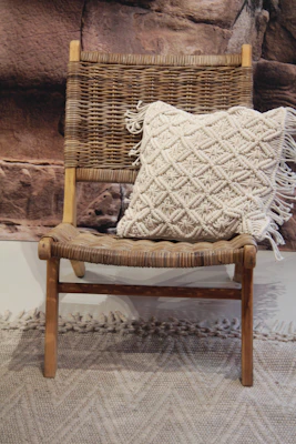 Hand-knitted throw pillow with textured patterns resting on a comfy armchair.