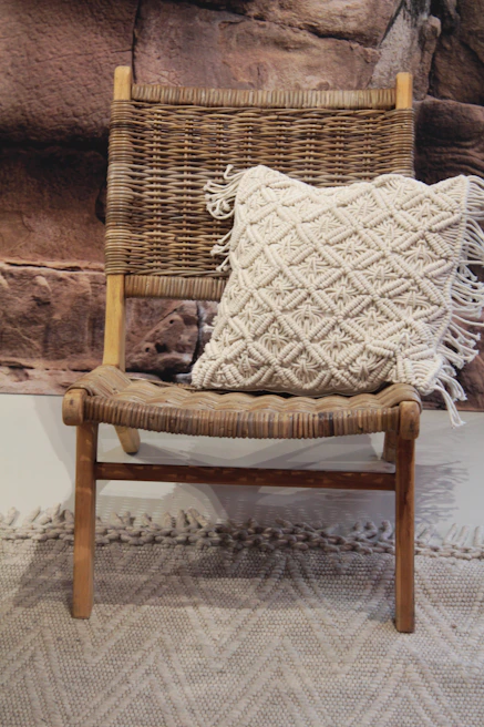 A cozy scene featuring a pink and earth-toned embroidered throw pillow on a rustic wooden chair