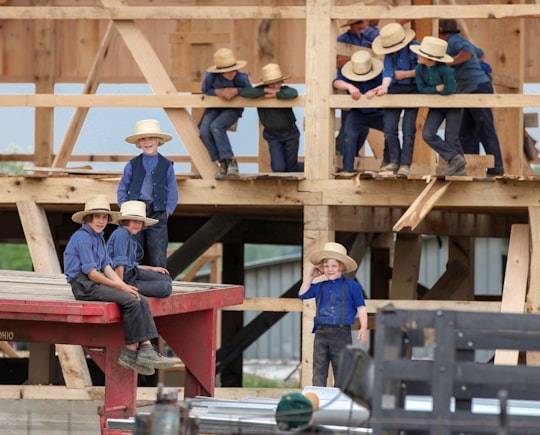 group of children wearing blue shirts and pants climbing on wood during daytime in Kidron United States