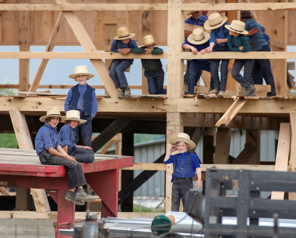 group of children wearing blue shirts and pants climbing on wood during daytime