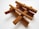Several cinnamon sticks are arranged in a crisscross pattern against a white background, showcasing their brown, textured surface and cylindrical shape.