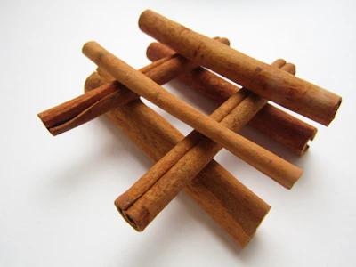 Cinnamon sticks arranged artistically with green leaves.