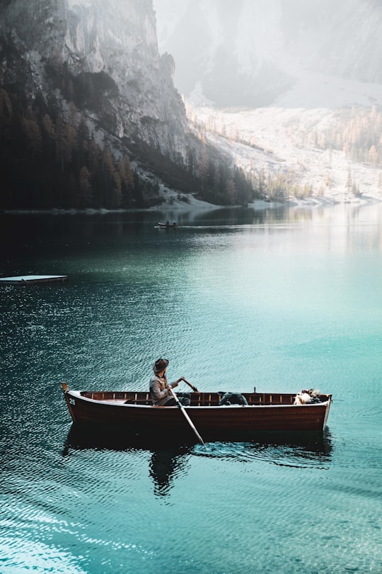 person on boat near mountain range in Lago di Braies Italy