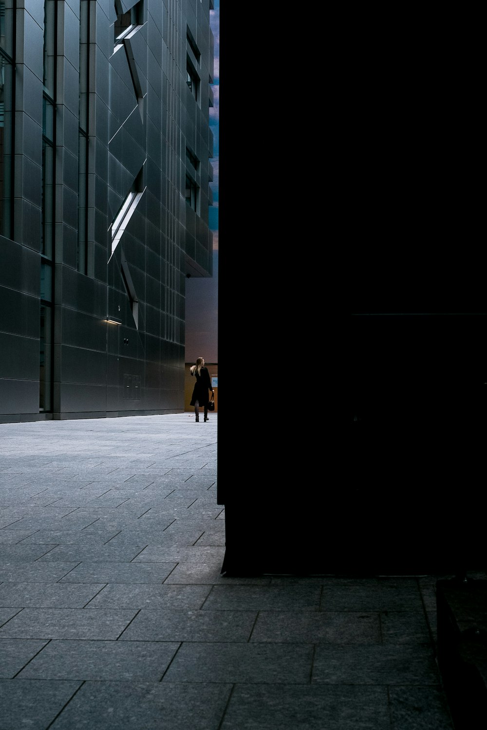 man wearing black dress while walking near building
