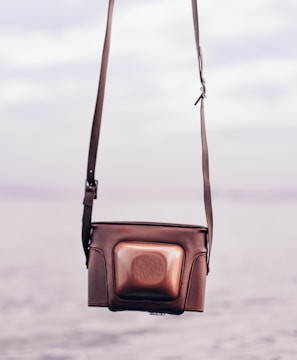 A casual crossbody bag resting on a city bench with blurred urban background.