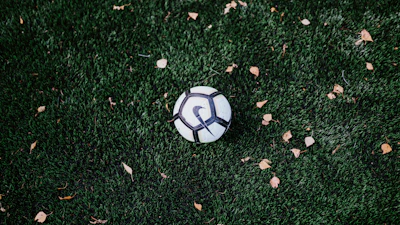 A close-up of a soccer ball resting on a green pitch, ready for kickoff.