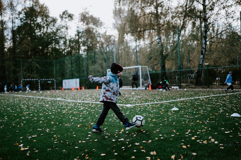 boy playing soccer during daytime