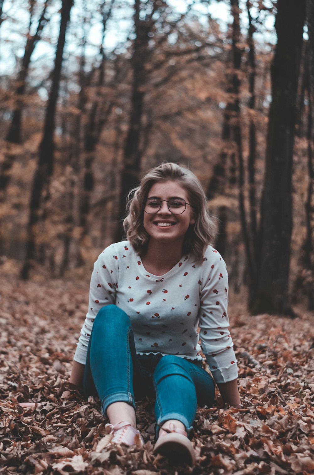 woman surrounded by brown leafed trees