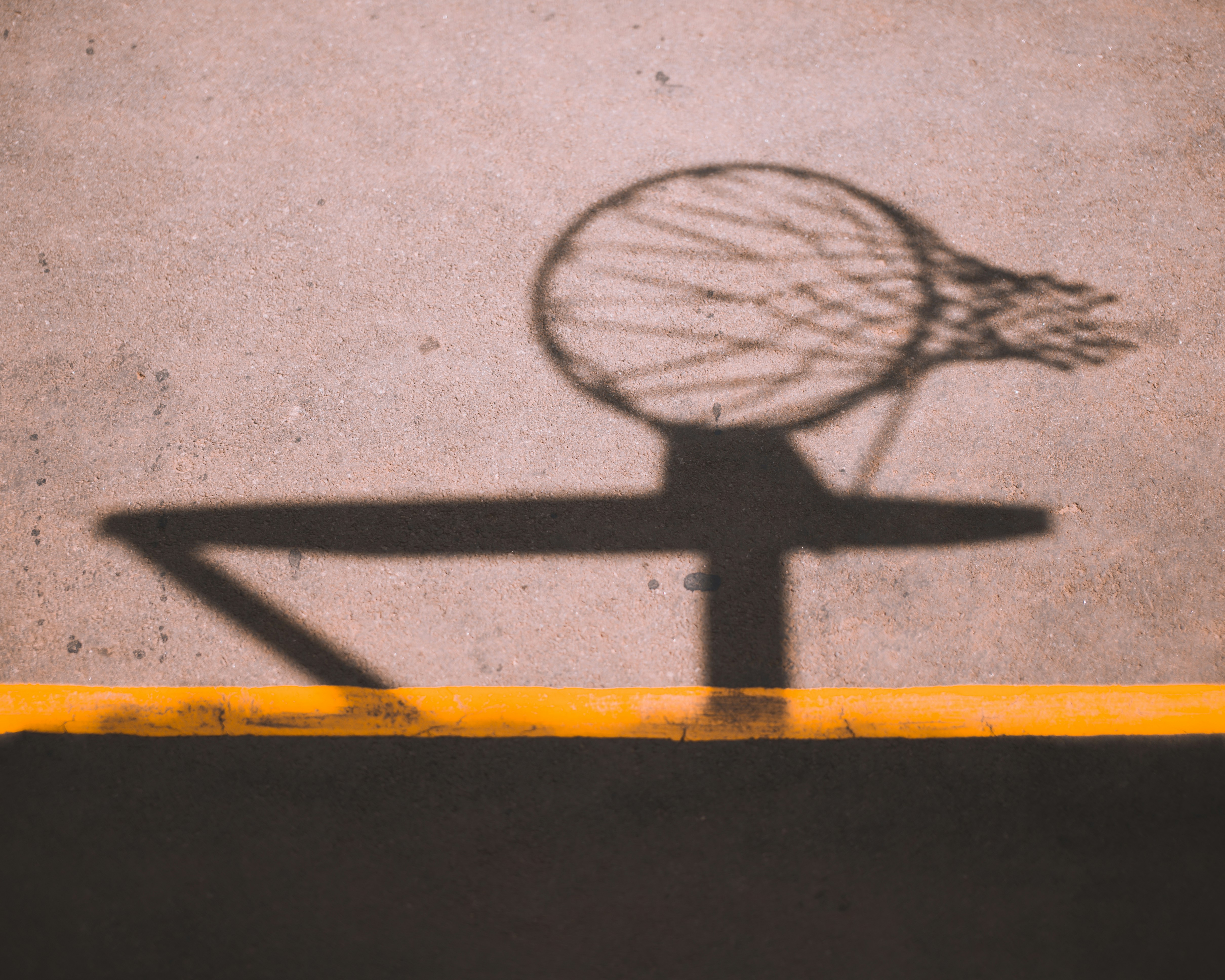 a shadow of a basketball hoop on the ground