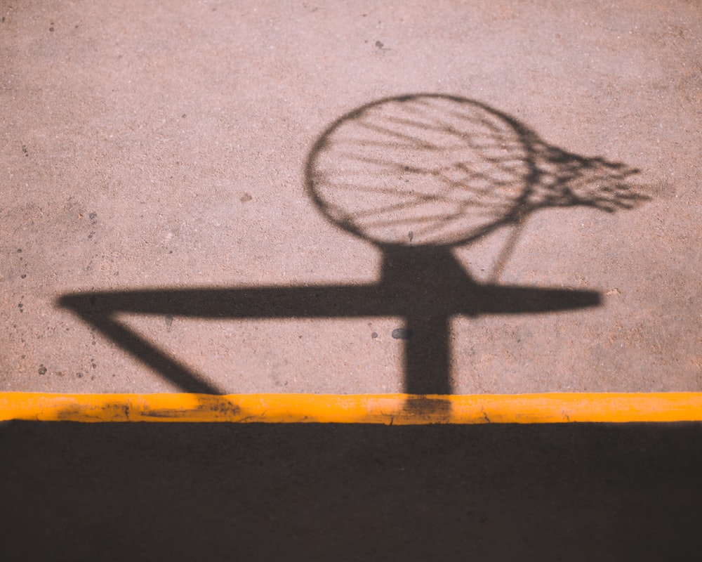 a shadow of a basketball hoop on the ground