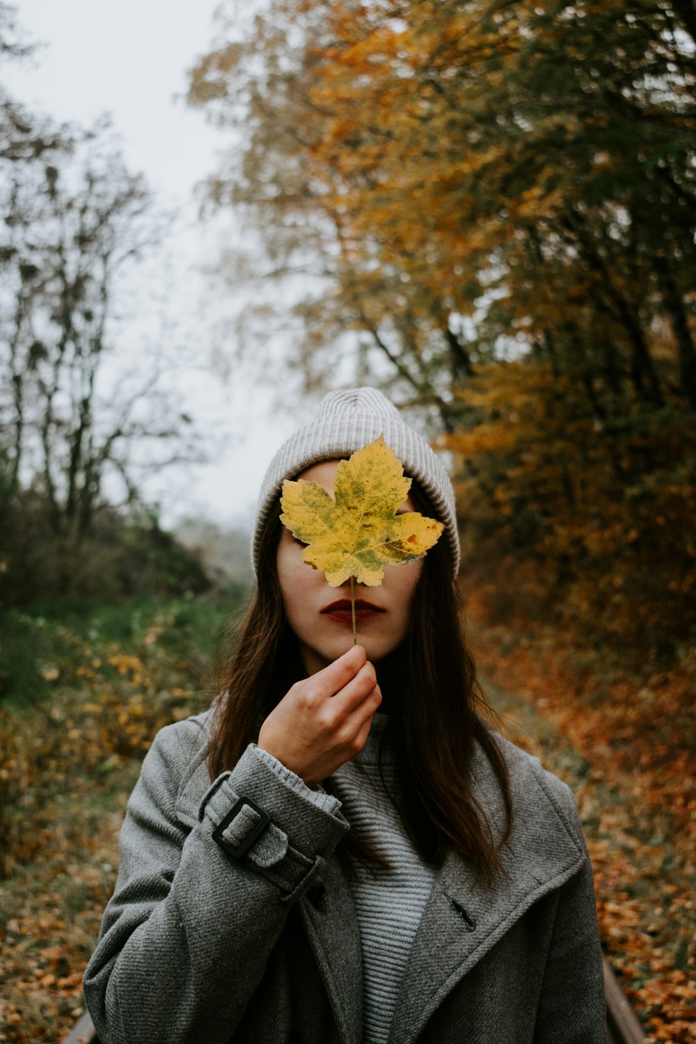 woman covering face with maple leaf