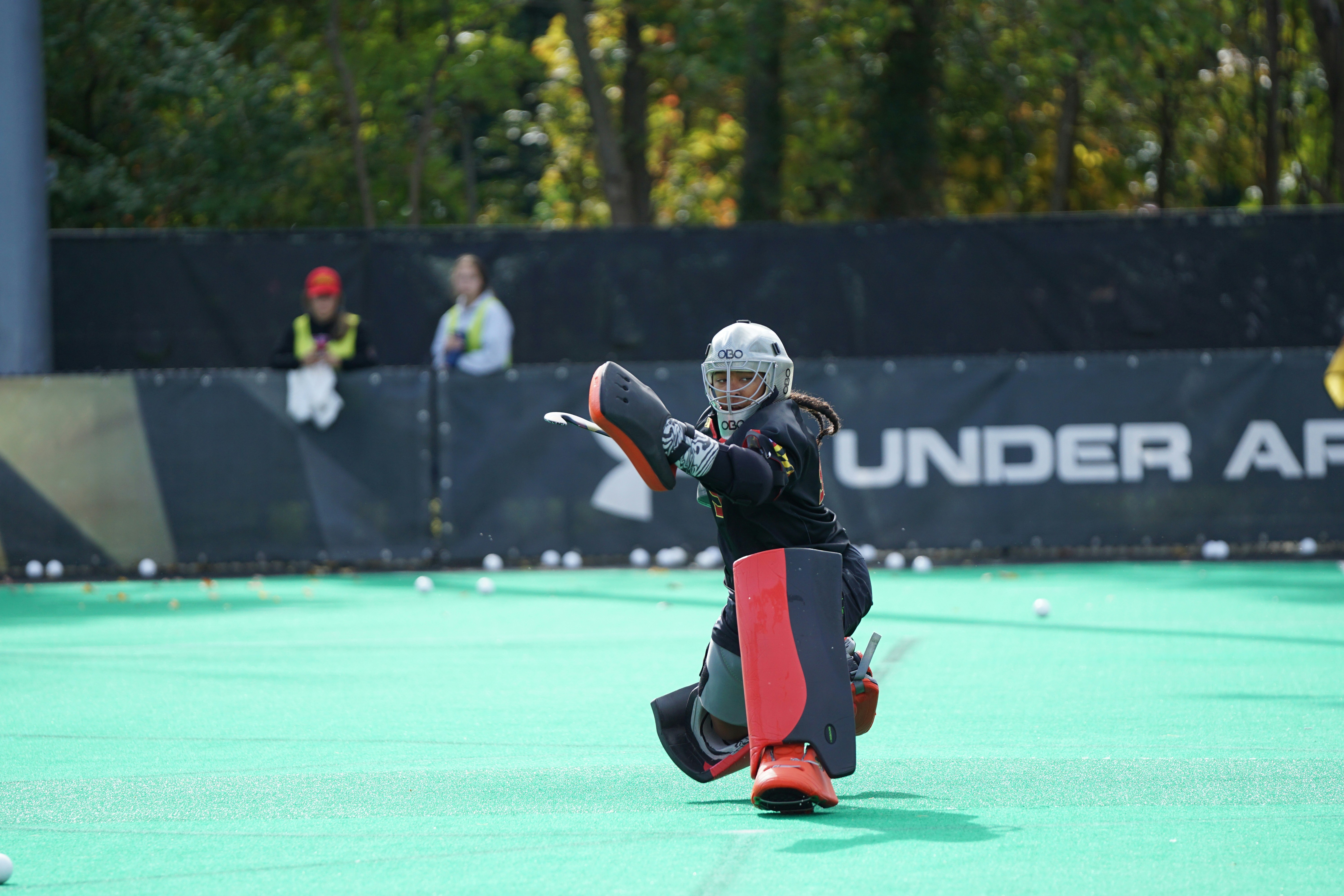 man wearing sports gears in middle of field during daytime field hockey teams background