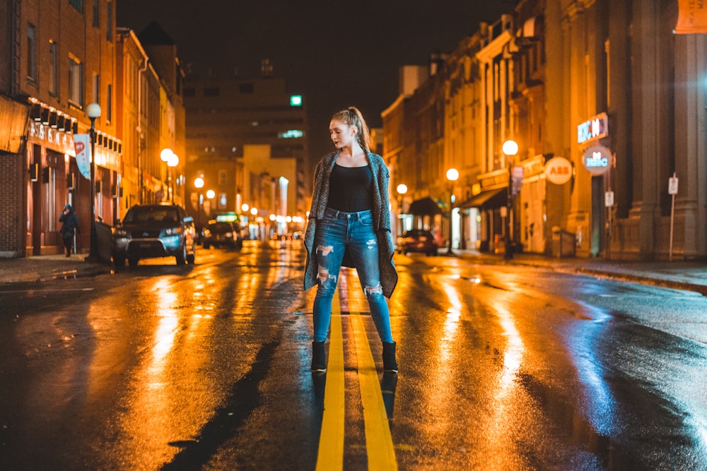 woman standing in middle of road during night time