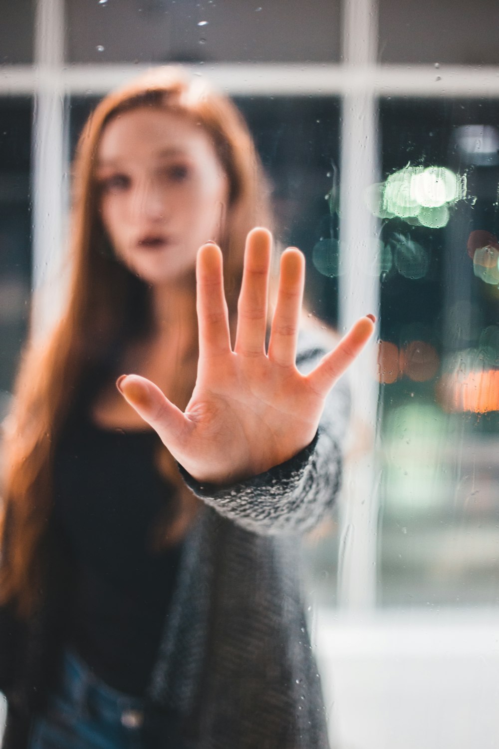 bokeh photography of woman touching glass wall